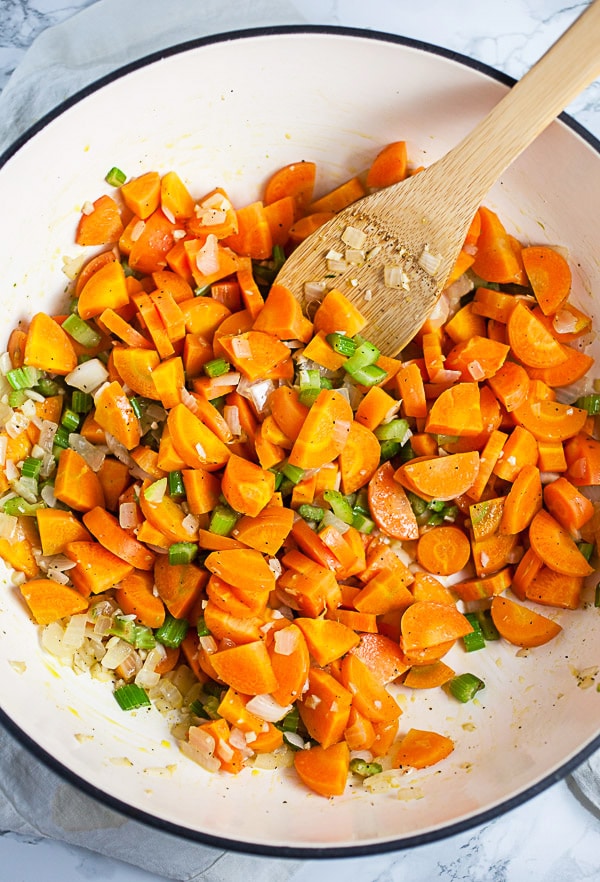 Garlic, onions, celery, and carrots sautéed in Dutch oven with wooden spoon.