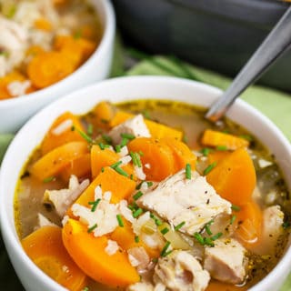 Turkey rice soup in white bowls in front of Dutch oven.