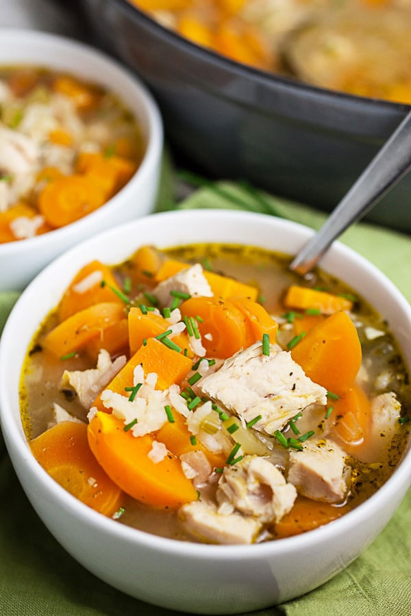 Turkey rice soup in white bowls in front of Dutch oven.