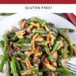 Green bean casserole with French fried onions on white plate with fork.