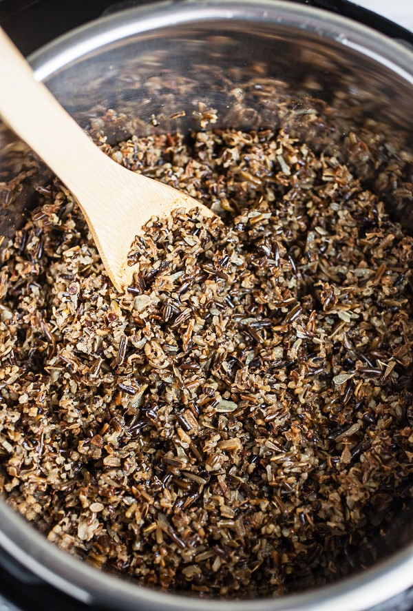 Cooked wild rice in Instant Pot with wooden spoon.