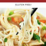 Bite of Asian chicken noodle soup lifted from white bowl with chopsticks.