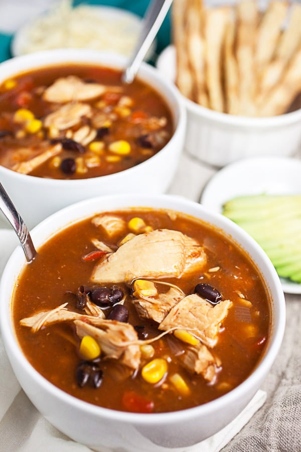 Tortilla soup in white bowls with spoons.