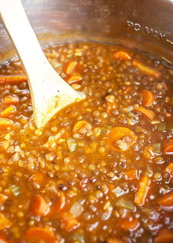 Lentil soup with carrots in Instant Pot with wooden spoon.