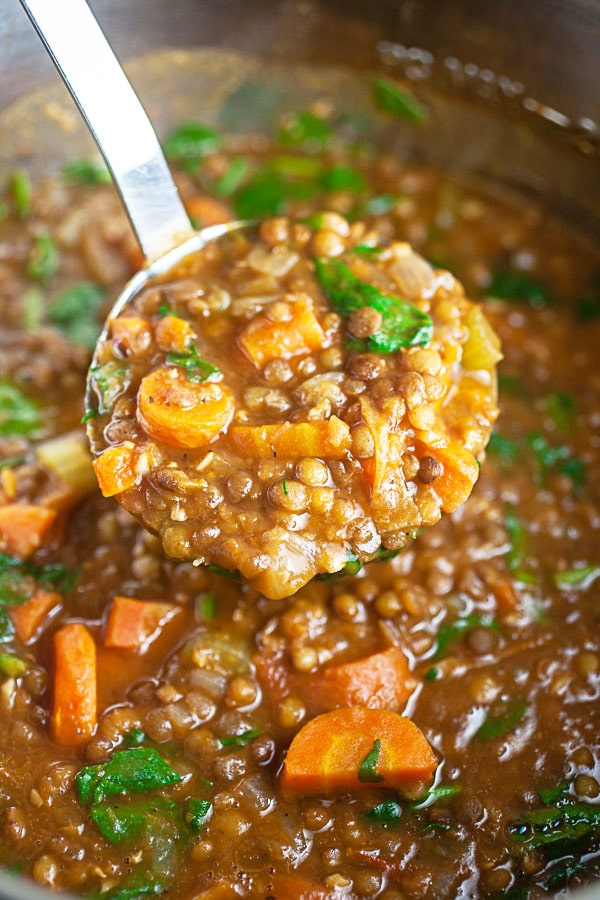 Scoop of lentil soup lifted from Instant Pot on metal ladle.