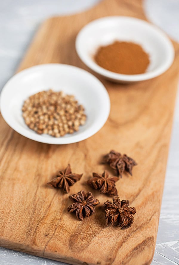 Star anise, coriander seeds, and Vietnamese cinnamon on wooden serving board.