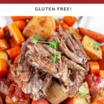 Beef pot roast with braised potatoes and carrots in white bowl with fork.
