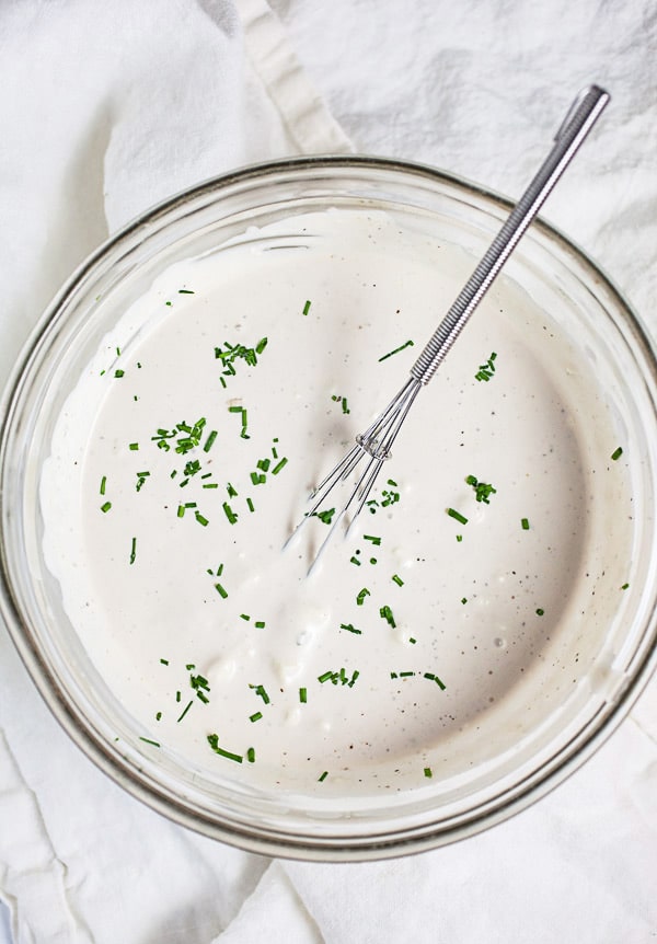 Blue cheese dressing in small glass bowl with whisk.