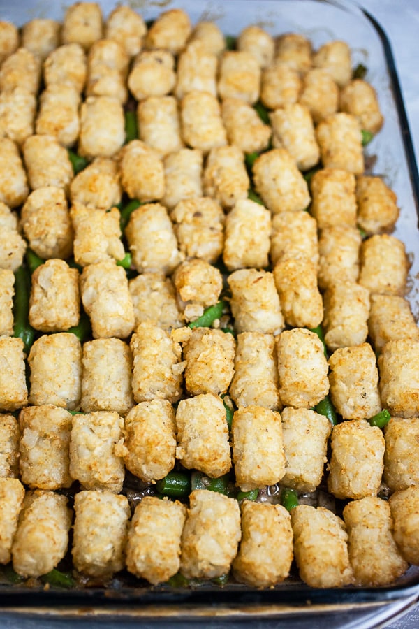 Cooked tater tot hotdish in glass baking dish.