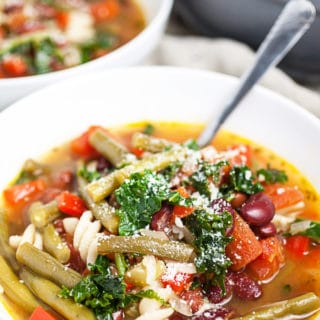 Tuscan vegetable soup with Parmesan cheese in white bowls.