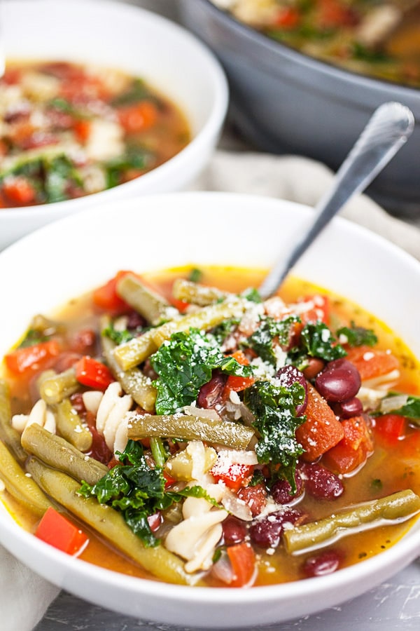 Tuscan vegetable soup with Parmesan cheese in white bowls.