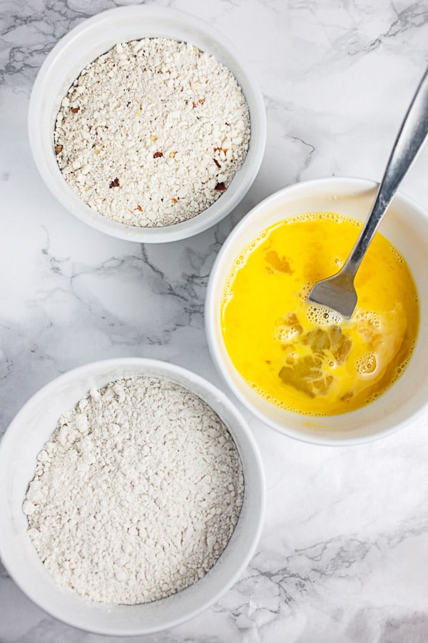 Flour, Panko breadcrumbs, and eggs in three separate white bowls.