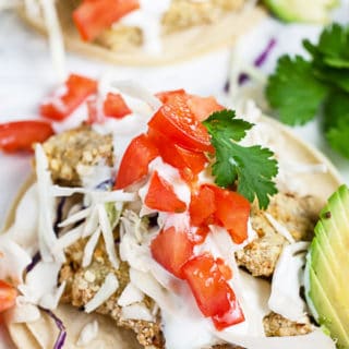Air fryer fish tacos on corn tortillas with Mexican crema, cabbage, tomatoes, and cilantro.