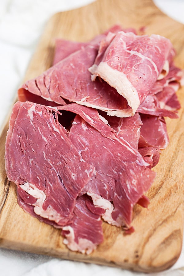 Slices of corn beef on wooden board.