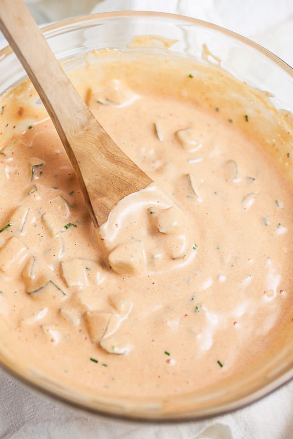 Homemade Thousand Island dressing in small glass bowl with wooden spoon.