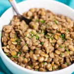 Instant pot lentils in small white bowl with fork.