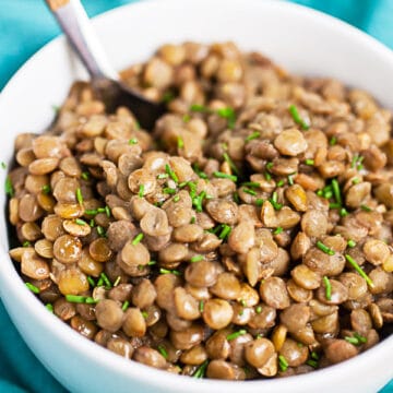 Instant pot lentils in small white bowl with fork.