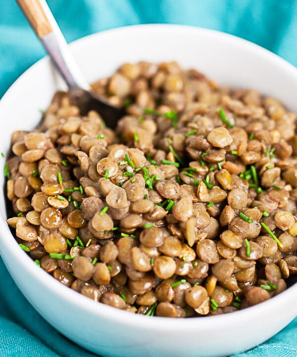 Instant pot lentils in small white bowl with fork.