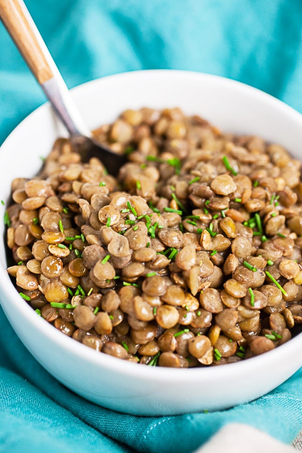 Instant pot lentils in small white bowl with fork.