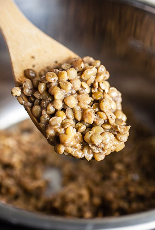 Cooked lentils on wooden spoon lifted from Instant Pot.