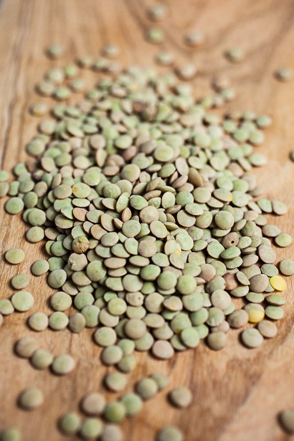 Dried green lentils on wooden board.