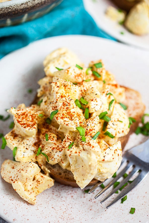 Mustard egg salad on white plate with fork.