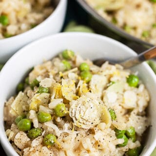 Lemon risotto with peas and artichokes in white bowls.