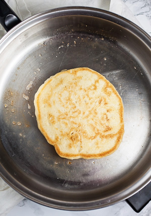 Pancake cooking in a stainless steel skillet.