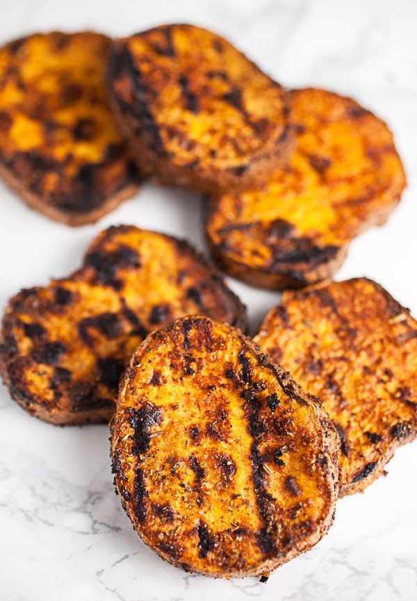 Grilled sweet potato rounds on white surface.