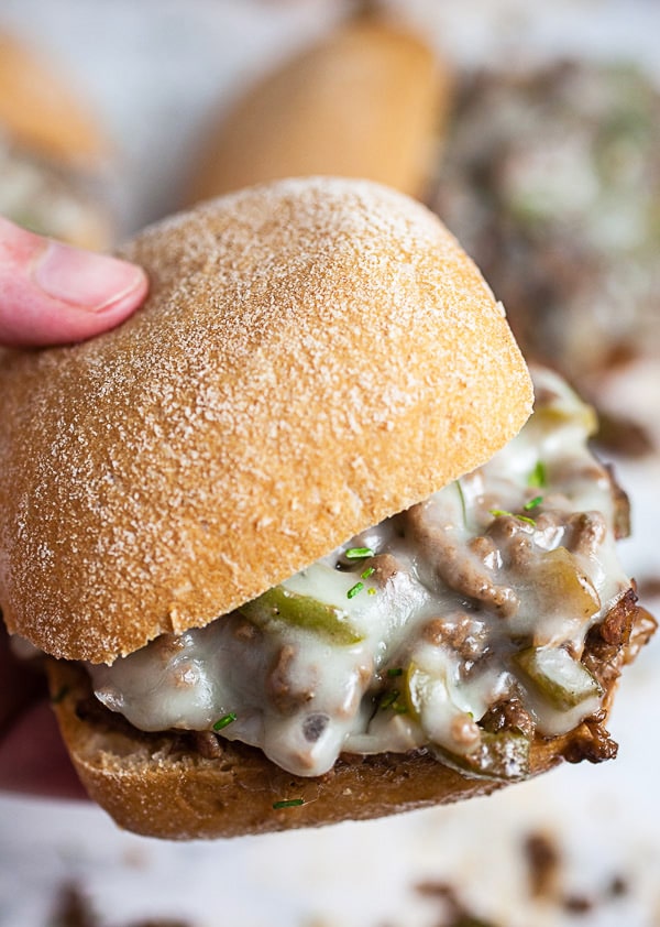 Hand holding Philly cheesesteak sloppy joe sandwich.