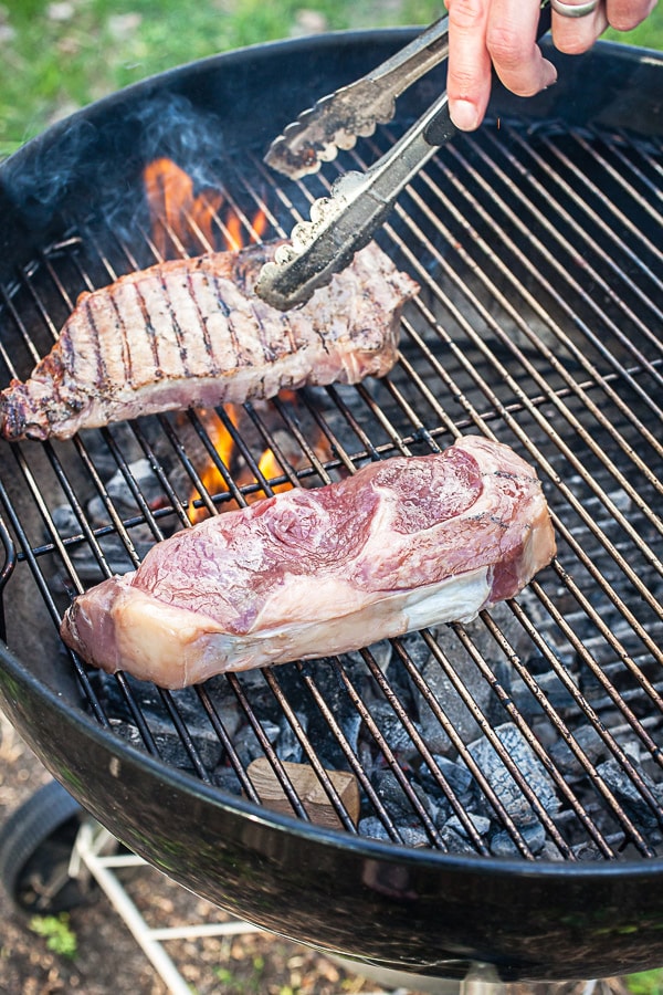 Ribeye steaks cooking on Weber grill.