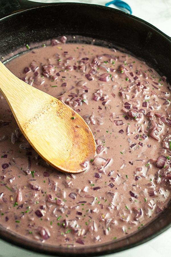 Red wine shallot sauce cooking in cast iron skillet.