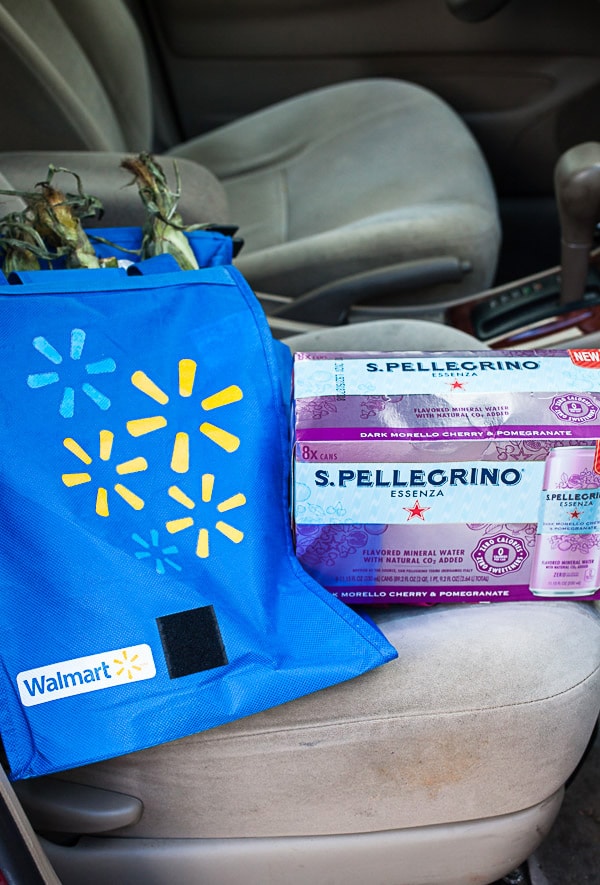 Reusable shopping bag and case of sparkling water in front seat of car.