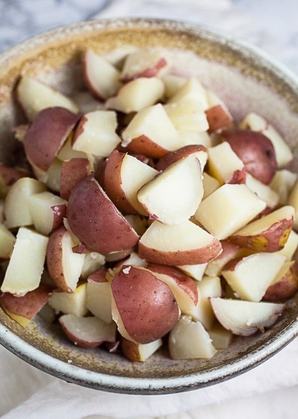 Cubed and cooked red potatoes in ceramic bowl.