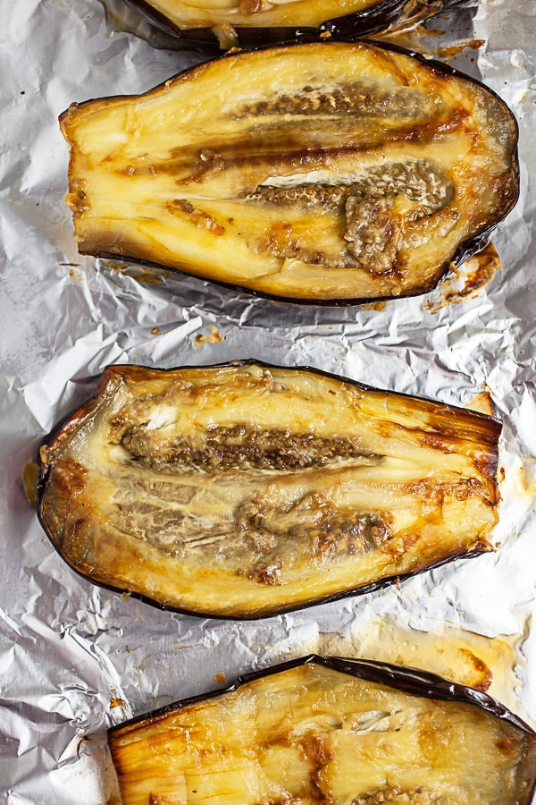 Roasted eggplant halves on foil lined baking sheet.
