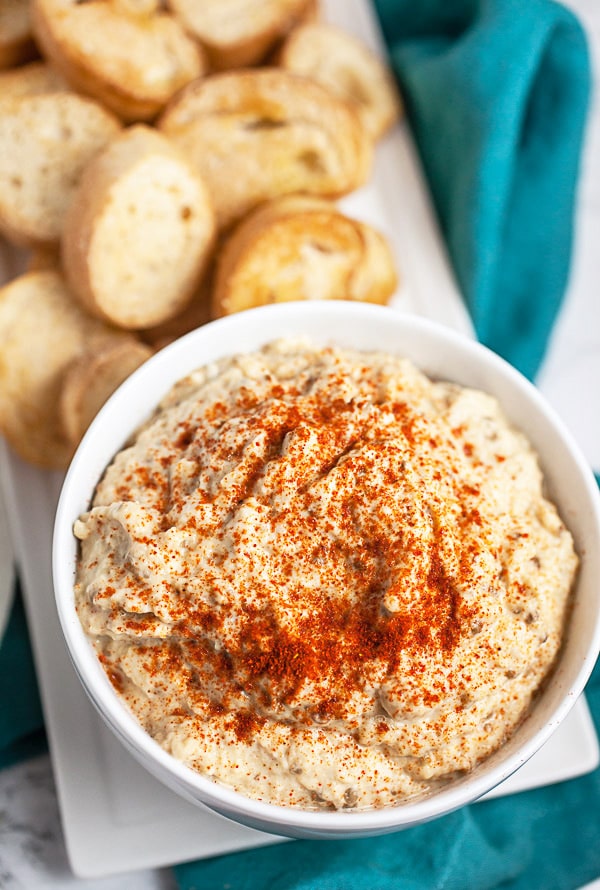 Baba ghanoush with smoked paprika next to crostini on serving platter.