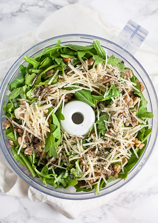 Fresh arugula, spinach, walnuts, Parmesan cheese, and olive oil in food processor.