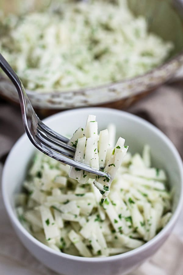 Forkful of coleslaw lifted from small white bowl.