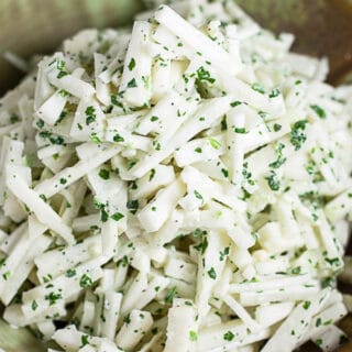 Kohlrabi slaw with cilantro lime dressing in ceramic bowl.