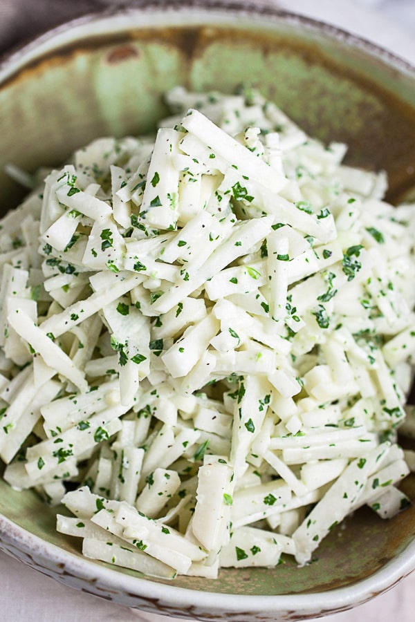 Kohlrabi slaw with cilantro lime dressing in ceramic bowl.