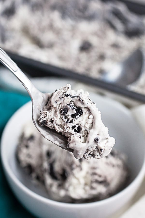 Spoonful of cookies and cream ice cream lifted from small white bowl.