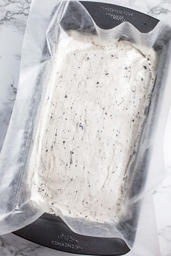 Unfrozen ice cream mixture in metal bread pan topped with wax paper.
