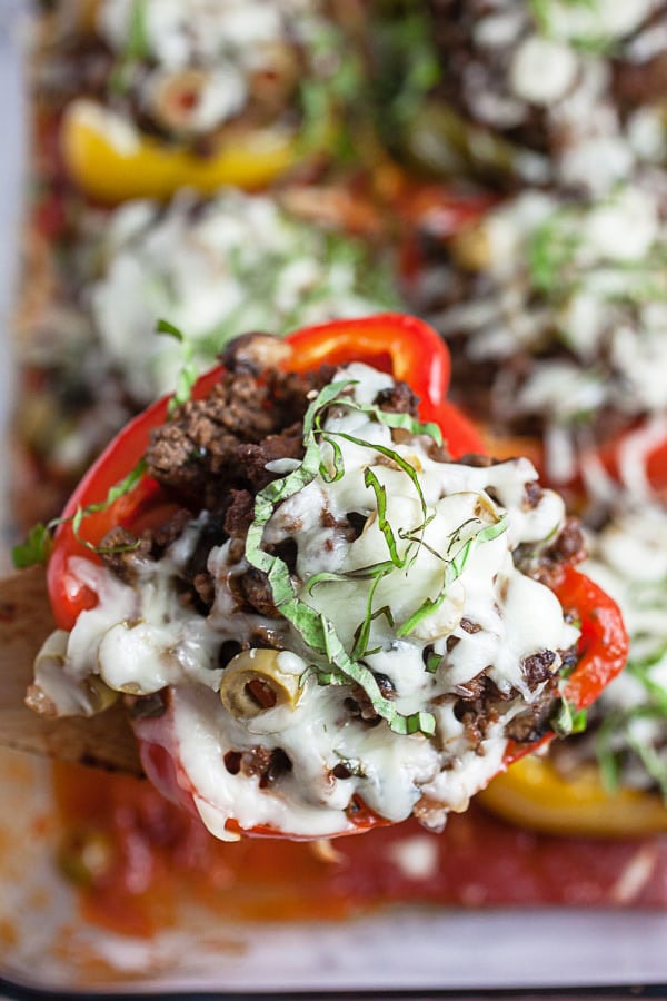 Baked stuffed red bell pepper lifted from glass baking dish.