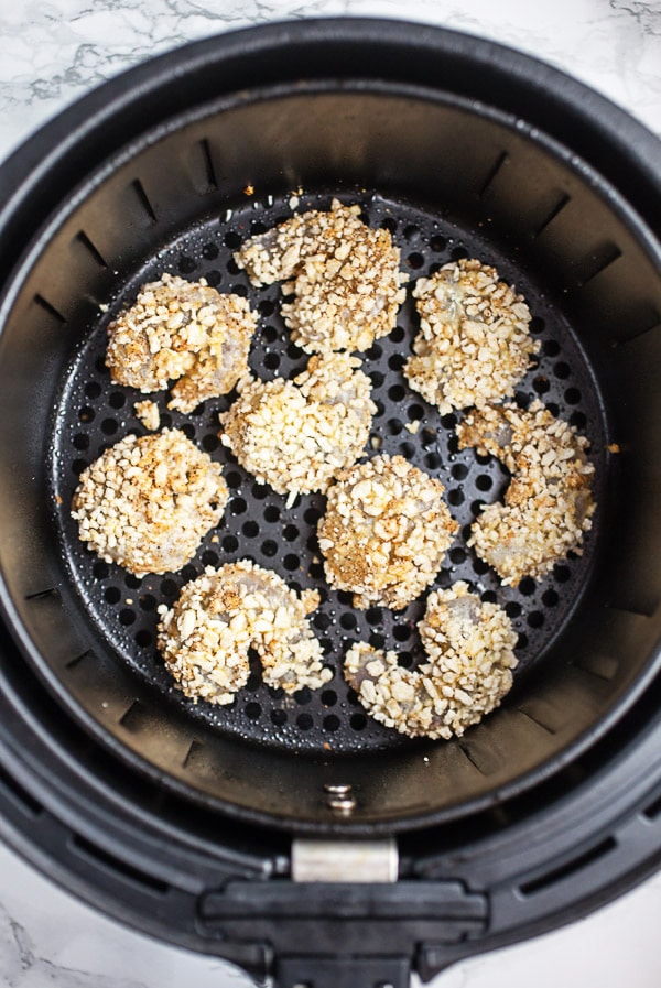 Uncooked breaded shrimp in air fryer basket.