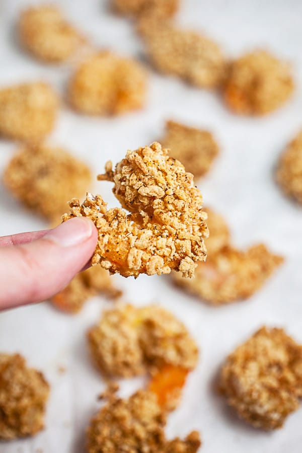 Fingers holding crispy air fried breaded shrimp.