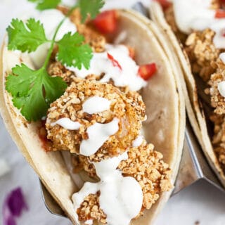 Breaded air fryer shrimp tacos with sauce and fresh cilantro.