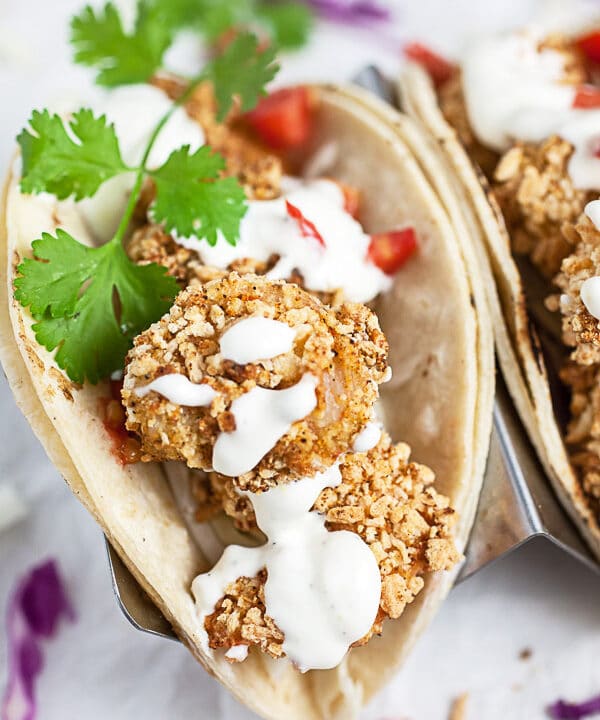 Breaded air fryer shrimp tacos with sauce and fresh cilantro.