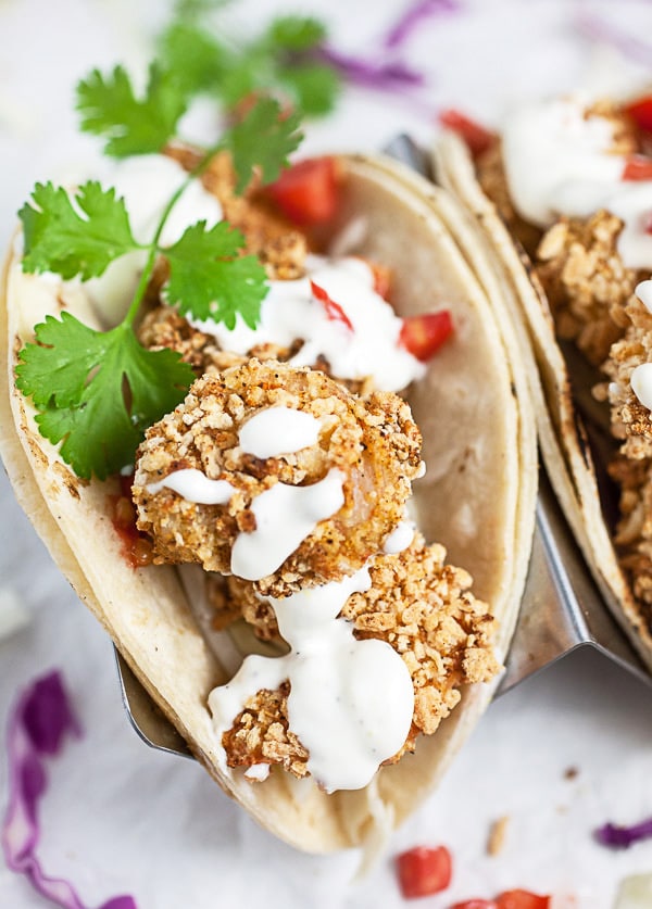 Breaded air fryer shrimp tacos with sauce and fresh cilantro.