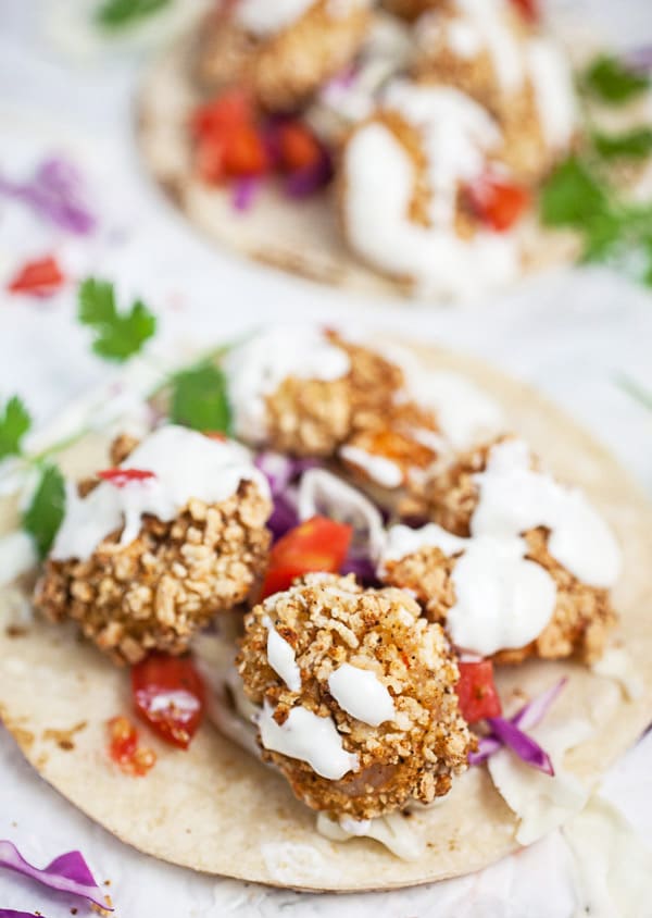 Air fryer shrimp tacos on corn tortillas with creamy sauce and fresh cilantro.