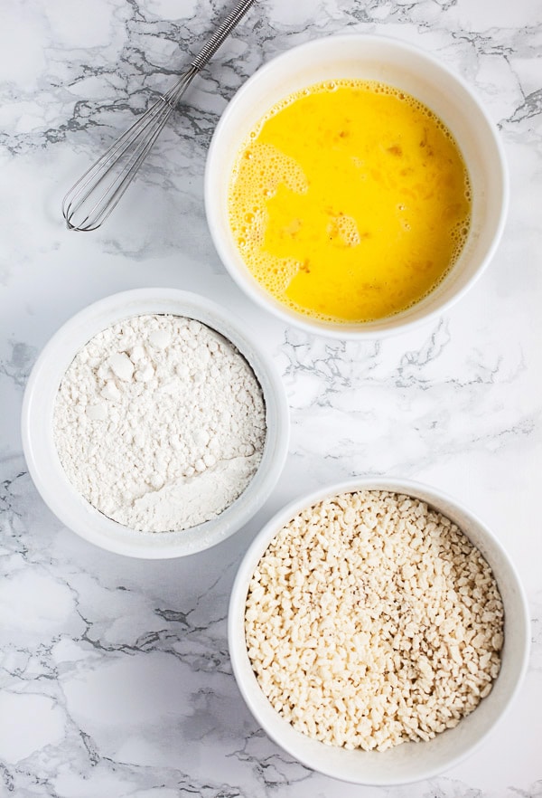 Panko breadcrumbs, flour, and eggs in three separate white bowls.